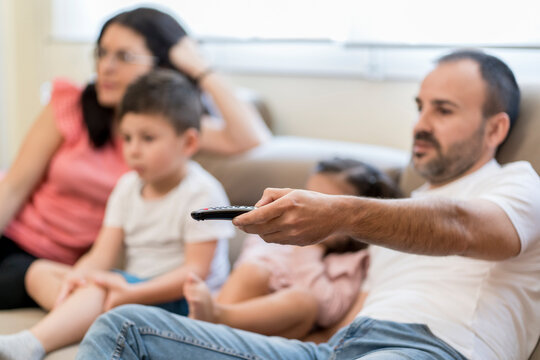 Father using controller while watching TV with family