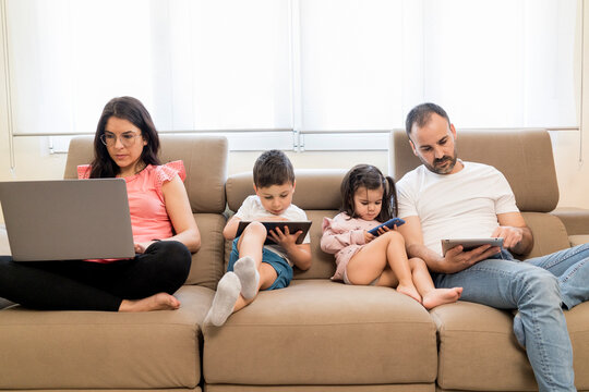Concentrated family using various gadgets in living room