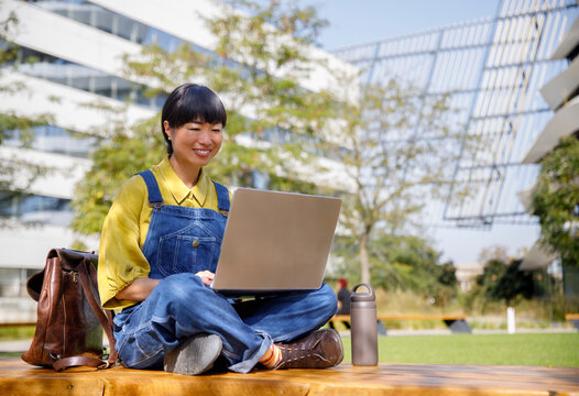 Asian woman working on laptop in college campus