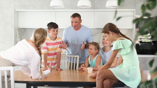 Friendly family gathered at table and cheerfully discuss past day. Mom, dad, three daughters and son solve important issue in friendly atmosphere
