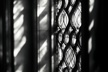 Black and white photo of a stained glass window, sunlight casting shadows on the wall.