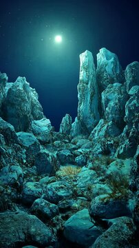Underwater landscape featuring towering rock formations illuminated by bright moonlight