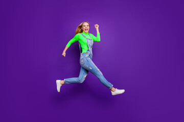 Full length photo of cheerful teenager running screaming wearing yellow turtleneck denim jeans overalls isolated over violet purple background