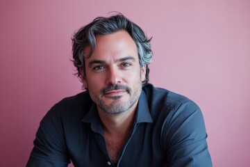 Obraz premium Confident Man with Stylish Hair Posing Against a Soft Pink Background