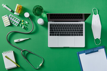 Medical equipment including stethoscope, syringe on green background