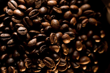 Richly roasted coffee beans create a captivating texture against a deep black background highlighting their natural sheen