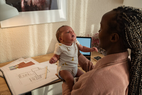 Mother looking at newborn at home office