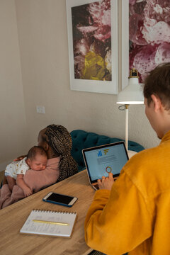 Man working on laptop while his wife lulling baby