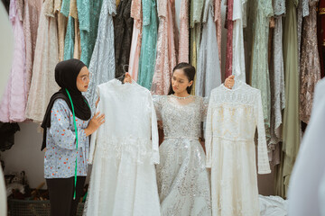 A bride excitedly explores various gown options with a stylist in a charming boutique