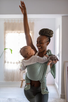 Cheerful woman working out and entertaining her baby