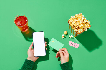 Smartphone with blank screen, popcorn and tickets online
