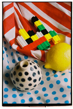 Colorful objects arranged on fabric with stripes and polka dots.