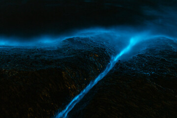 Bioluminescence from micro marine organisms. Shallow water on rocks. 