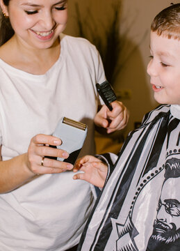 The barber lets the boy touch the razor.