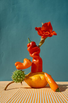 Creative arrangement of colorful vegetables and a flower on table.