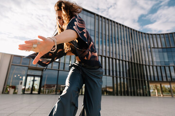 A dancer poses dramatically outdoors in front of a modern building