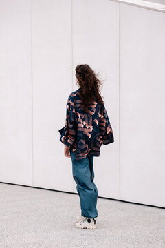 A woman in a patterned jacket and blue trousers backside