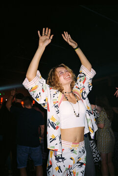 Young woman dancing joyfully in colorful outfit at a lively party