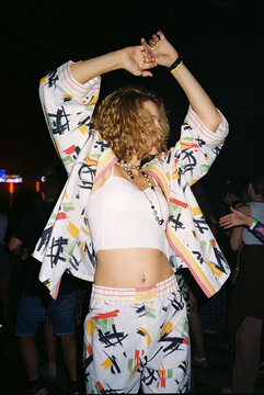 Young woman dancing joyfully in colorful outfit at lively music fest