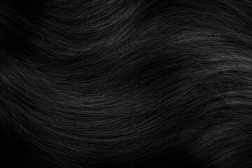 Brunette or black hair. Female long dark hair in black. Beautifully laid curls. Closeup texture in a dark key. Hairdressing, hair care and coloring. Shading gray hair. Background with copy space.