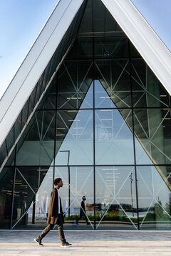 Man walking past modern glass building