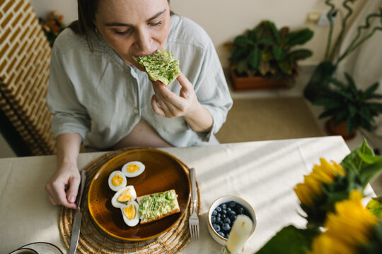A pregnant woman eating a toast with mashed avocado