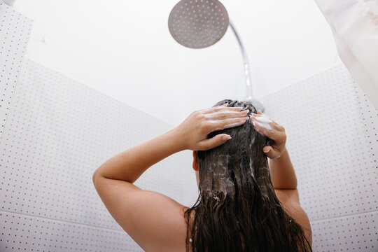 Bottom cropped view of woman washing hair during taking shower