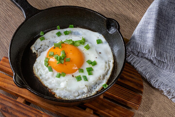 Fried egg with green onions in a cast iron skillet, top view