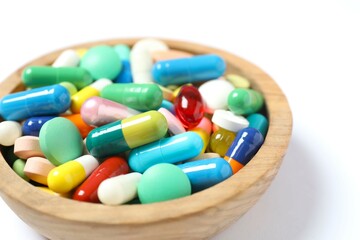Various pills in a bowl on white background
