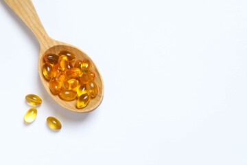Capsule of omega 3, 6, 9 fish oil, vitamin, food supplement in wooden spoon on white background 