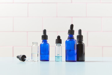 Various glass dropper bottles standing over tiled background