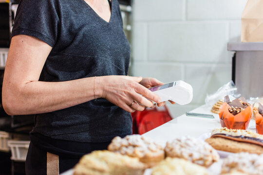 Bakery employee processing payment with card reader
