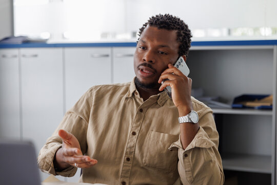 Serious businessman talking on mobile phone in office