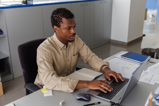 Serious businessman using laptop at desk in office