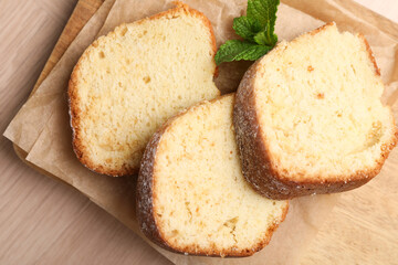 Pieces of freshly baked sponge cake and mint on wooden table, top view