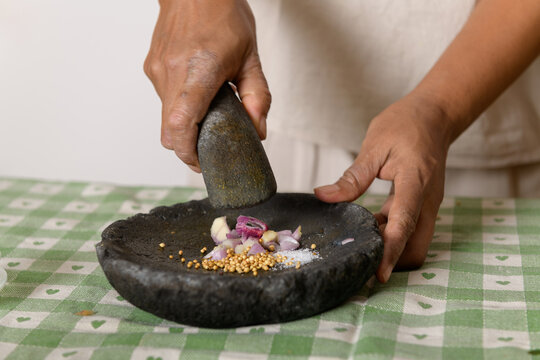 Asian woman's hands grinding the spices with stone mortar Cobek - Powered by Adobe