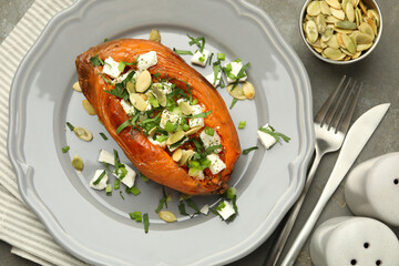 Tasty cooked sweet potato with feta cheese, pumpkin seeds and green onion on grey table, top view