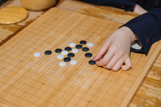 Hand Playing Go on Wooden Board
