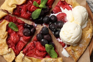 Tasty galette with berries, ice cream and mint on table, top view