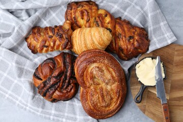 Different delicious pastries, butter and knife on grey table, top view