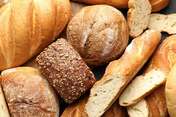Whole and cut loafs of bread on table, closeup