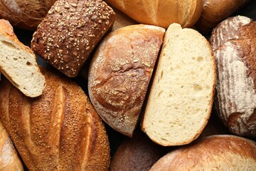 Whole and cut loafs of bread on table, closeup