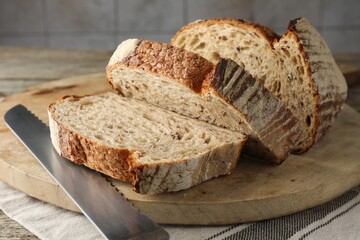 Cut loaf of fresh bread and knife on table, closeup