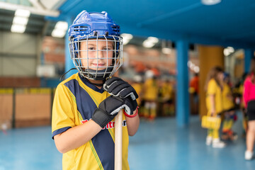 Young roller hockey player posing with stick and helmet in rink