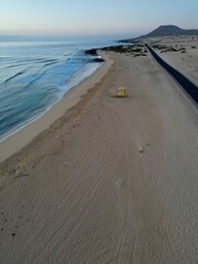 Aerial view of a coastal road through the sand dunes with sea views and blue sky background. Taken in Fuerteventura. 
