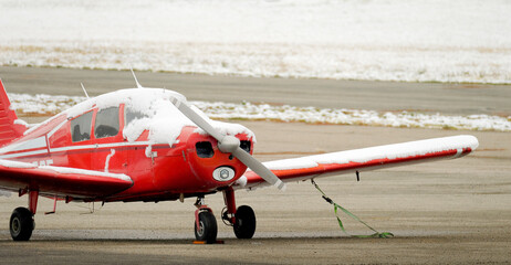 Small Red Airplane Single Engine Private Plane on Runway Covered in Snow in the Winter Wintery Snowy