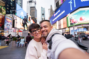 Happy tourists couple taking selfie in times square, new york city