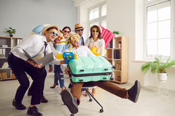 Funny happy people coworkers having fun in office with suitcase rejoicing the sale on tour. Overjoyed company employees going on summer holiday trip. Vacation and travelling concept.