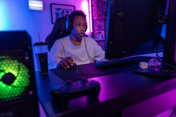Focused Teen Gamer at Computer in Vibrant Gaming Setup