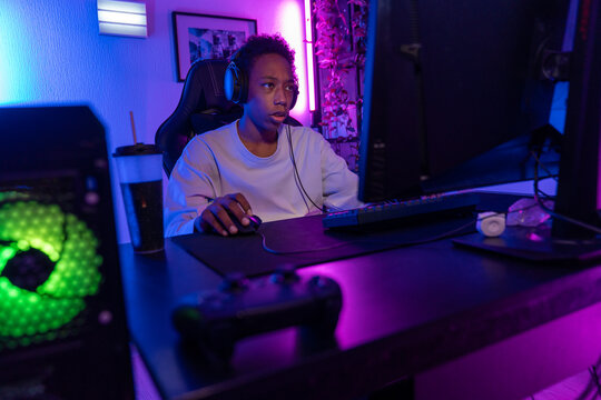 Focused Teen Gamer at Computer in Vibrant Gaming Setup
